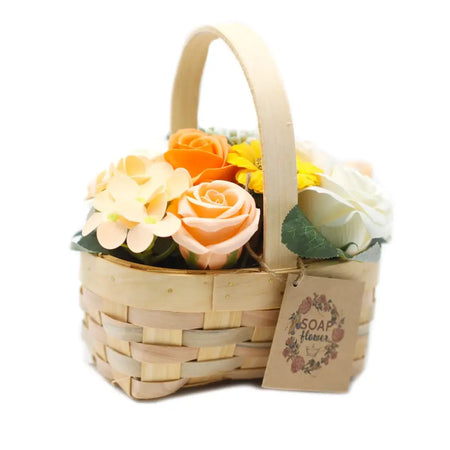 A light wooden wicker basket holding a bouquet of colorful soap flowers in orange, peach, yellow, and white shades