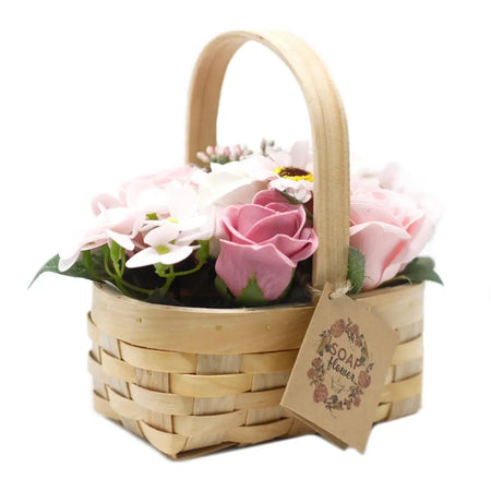 A light brown wicker basket filled with pink and white soap flowers in a medium size arrangement