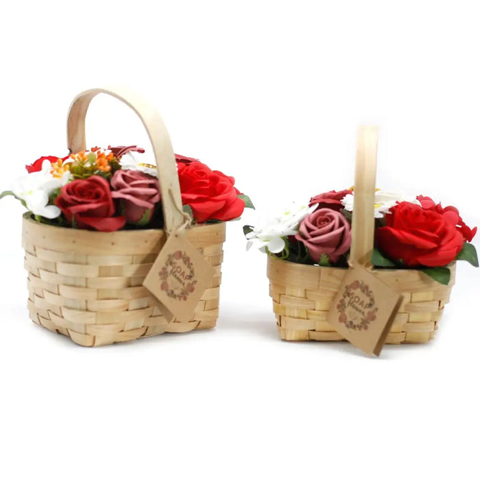 Two woven wicker baskets each hold soap flowers in red and white with green leaves in a medium size arrangement