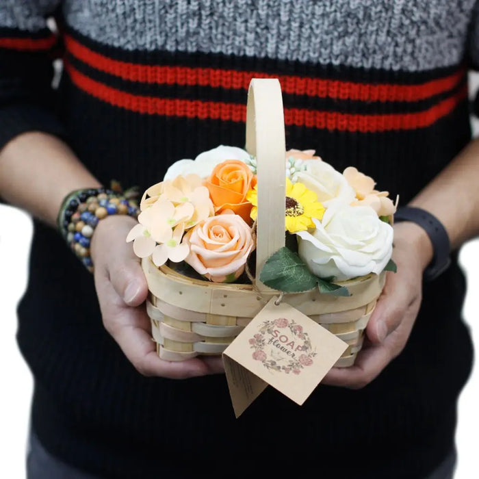 A woven wicker basket filled with peach orange white and yellow soap flowers in a medium red basket