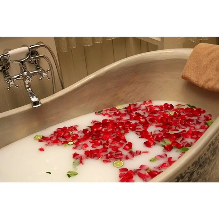 A vintage chrome faucet with white ceramic handle next to an oval tub with pink soap flowers shaped like roses