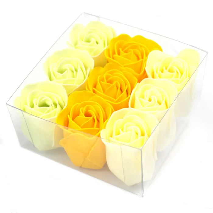 A clear plastic box of nine soap flowers shaped like spring roses in yellow and pale cream hues