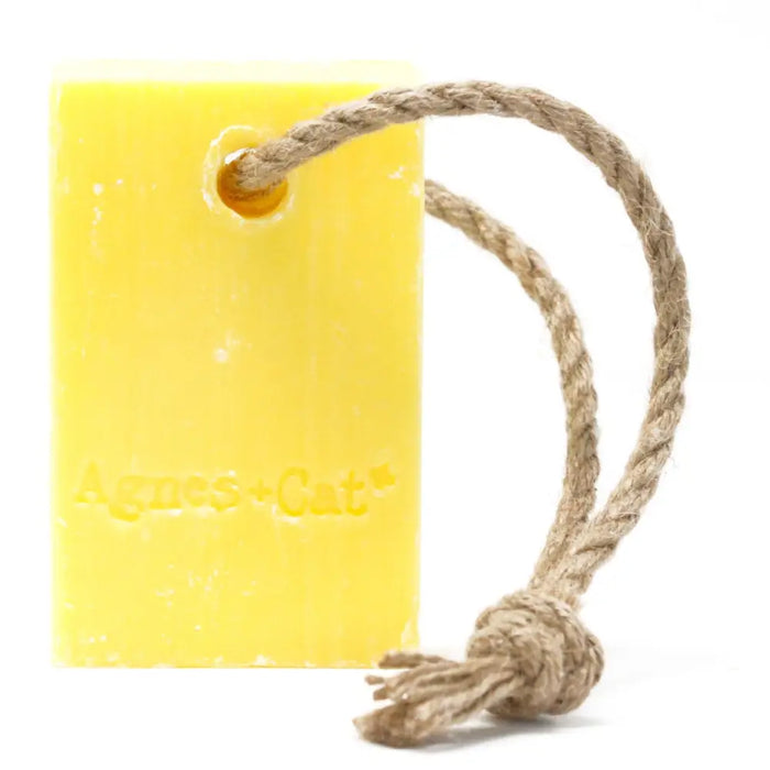 Bright yellow soap on a rope with natural twine and agnes cat brand name embossed fresh citrus scent