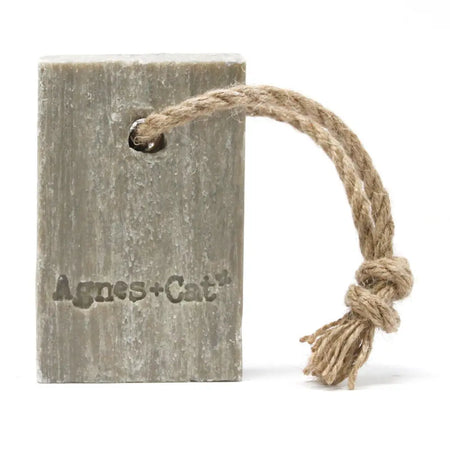 A rustic gray soap on a rope with a textured surface and agnes cat brand, scented with white fig