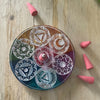 Soapstone incense holder circular design with carved chakra symbols in clear resin against earthy tone background