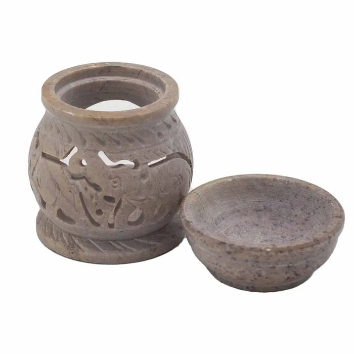 A carved soapstone oil burner with elephant and animal motifs and a matching speckled stone bowl