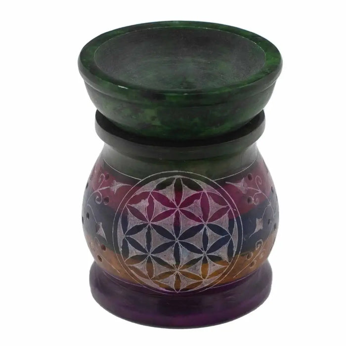 A hand-carved soapstone oil burner in green and purple with a flower of life design etched on its rounded body