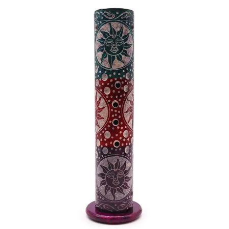 A dark green and red soapstone tower incense holder with carved sun faces and circular designs