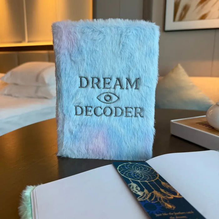 A fluffy light blue faux fur dream decoder soft book with dark gray embroidery and an eye symbol on the cover