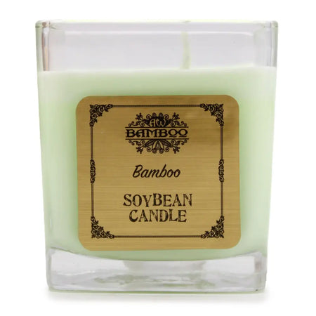 A square glass jar holds a pale green soy wax candle with a wooden label bamboo by aw bamboo measuring 5cm