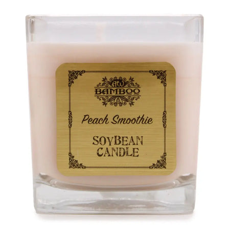 A square glass soy wax jar candle in soft pink with an ornate gold peach smoothie label by bamboo, 5cm wide