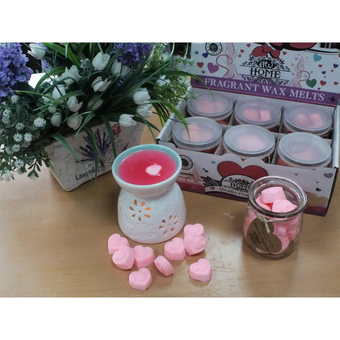 White ceramic soy wax melt warmer with pink heart-shaped wax melt and decorative cut-out patterns inside