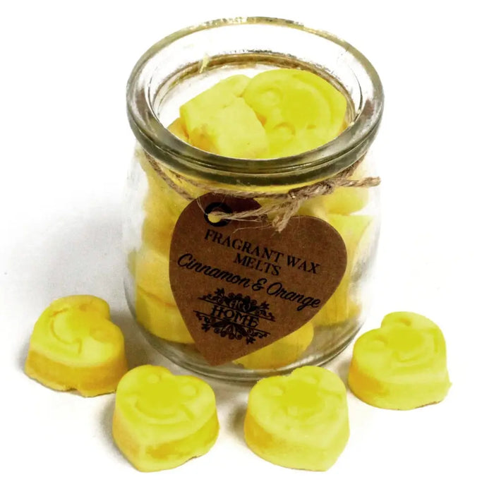 Bright yellow heart-shaped soy wax melts with cinnamon and orange scent in a clear glass jar with a rustic tag