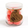 A clear glass jar of pink heart-shaped soy wax melts sealed with lid and tagged with twine for classic rose scent