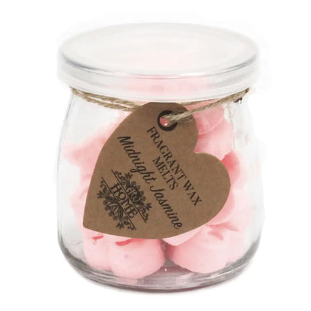 A clear glass jar of pink heart-shaped soy wax melts labeled midnight jasmine by home brand