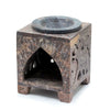 Square soapstone oil burner with dark circular well and elephant-shaped carved arched cutouts along its sides