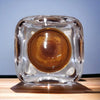 Clear glass cube tealight holder with circular amber interior for use as a two-tone glass tealight holder