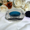 Clear glass tealight holder with teal interior and colony engraving on the base for a stylish glass tealight display
