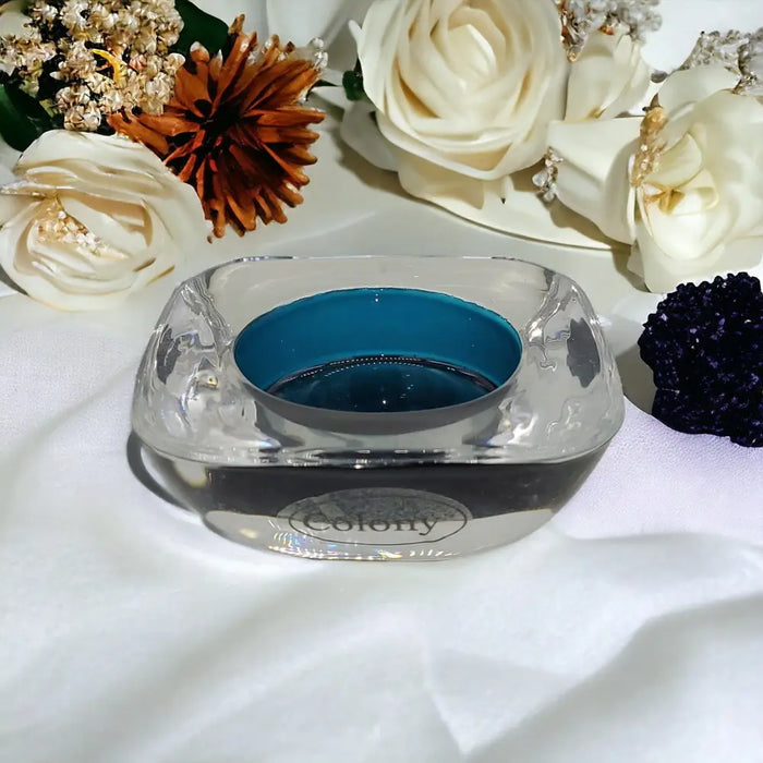 Clear glass tealight holder with teal interior and colony engraving on the base for a stylish glass tealight display