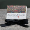 Black satin ribbon tied in a bow with sterling silver and 18ct yellow gold angel wings earrings background