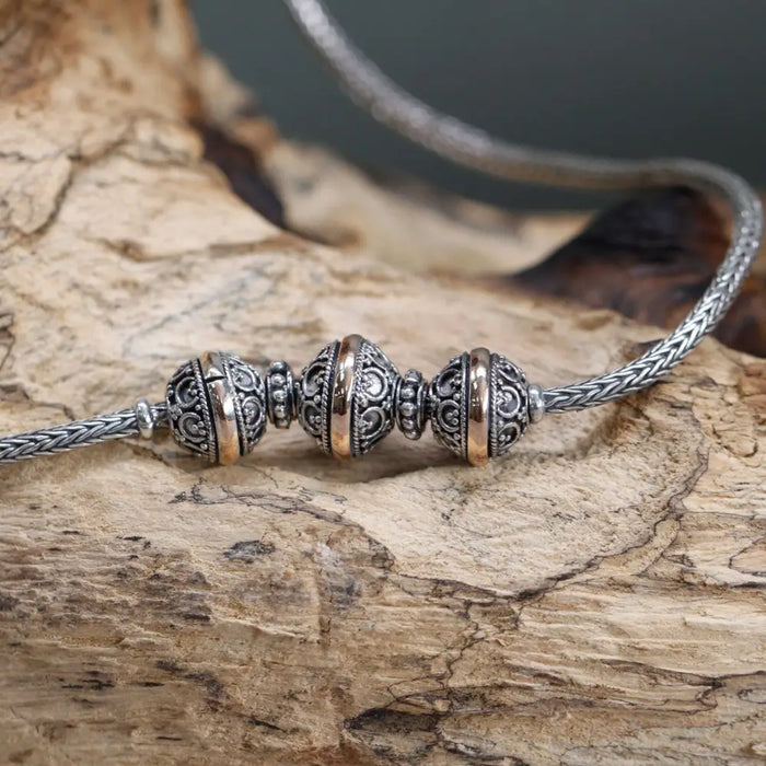 Sterling silver and 18ct yellow gold necklace with charm beads and spacers on a braided metal chain