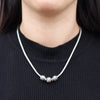 Sterling silver necklace with three charm beads and two spacers on a white cord featuring 18ct yellow gold accents
