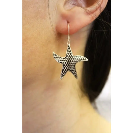 Sterling silver earrings shaped like silver starfish with a textured dotted pattern