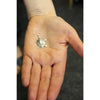 A delicate sterling silver turtle-shaped earring with intricate detailing and a small hook for wearing silver earrings