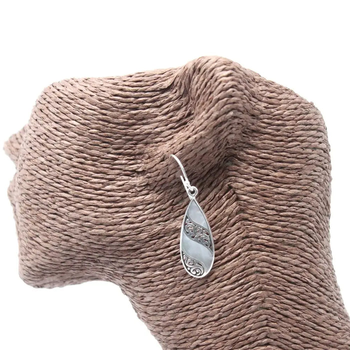 Sterling silver teardrop earrings with intricate scrollwork and a smooth light mother of pearl stone inset