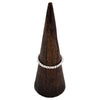 A sterling silver stackable ring with a beaded design sits on a dark wooden cone display