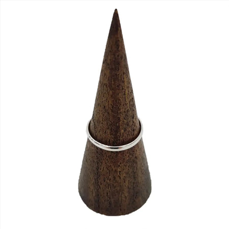 A sterling silver stackable ring with a plain d shape design displayed on a dark brown wooden cone stand