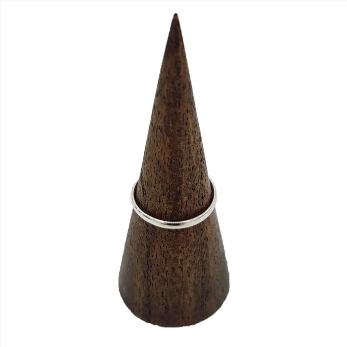 A sterling silver stackable ring with a plain d shape design displayed on a dark brown wooden cone stand