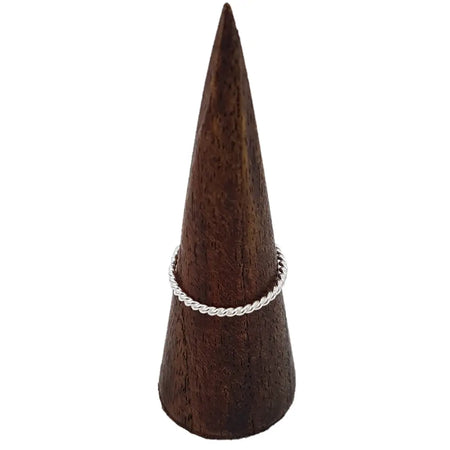 A sterling silver stackable ring with a delicate rope design displayed on a dark wooden cone