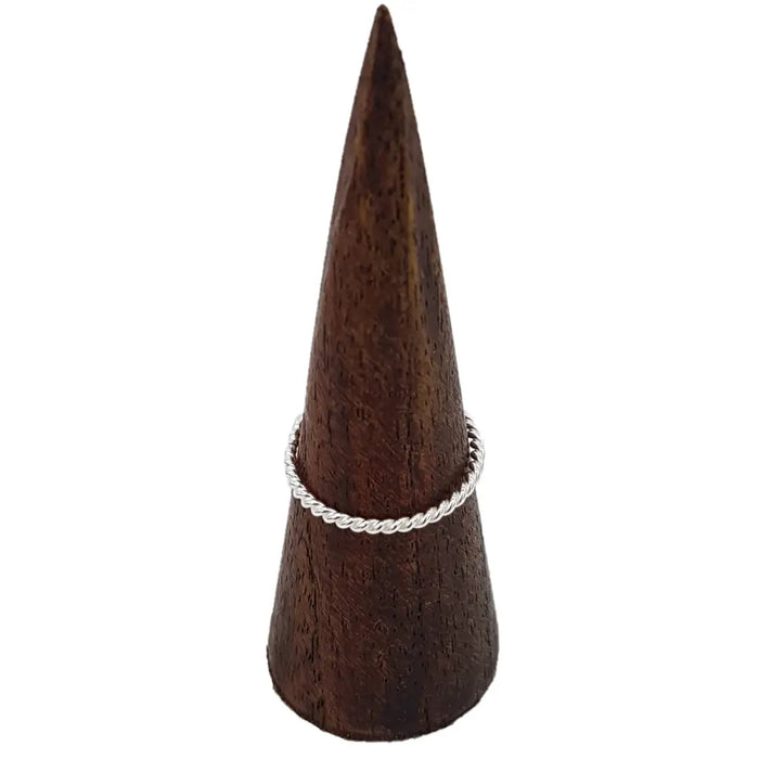 A sterling silver stackable ring with a delicate rope design displayed on a dark wooden cone