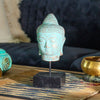 Buddha head figurine in a green-copper finish with an antique stone effect and iron stem.
