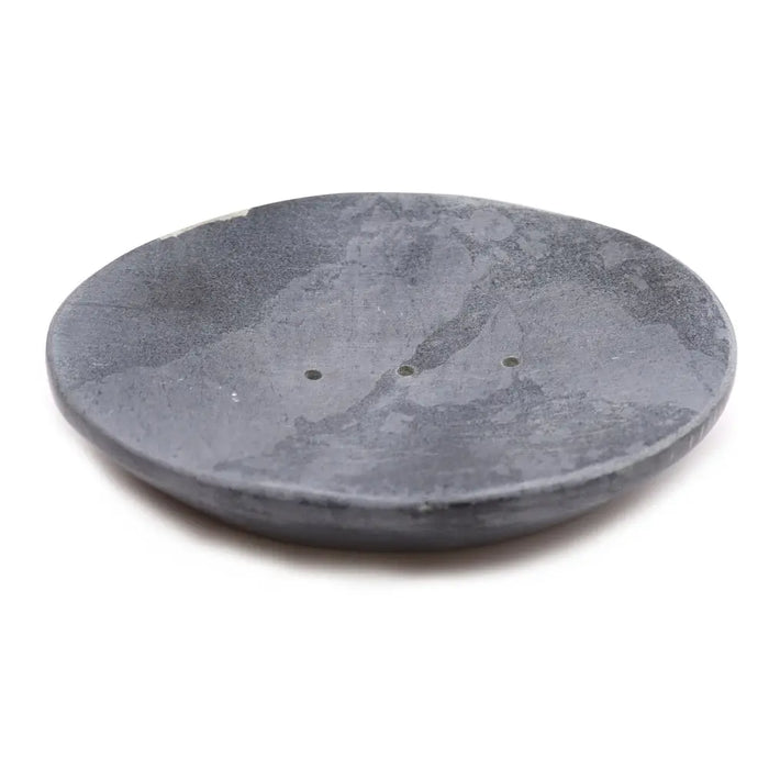 Gray soap dish made of soapstone with a classic oval shape and three small drainage holes and a smooth texture