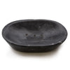 Black marble soap dish in an oval shape made of matte stone with a slightly uneven surface and drainage holes