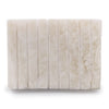 Stone soap dish in white onyx with vertical grooves and subtle natural veining on an off-white rectangular tile