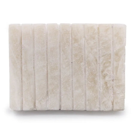 Stone soap dish in white onyx with vertical grooves and subtle natural veining on an off-white rectangular tile