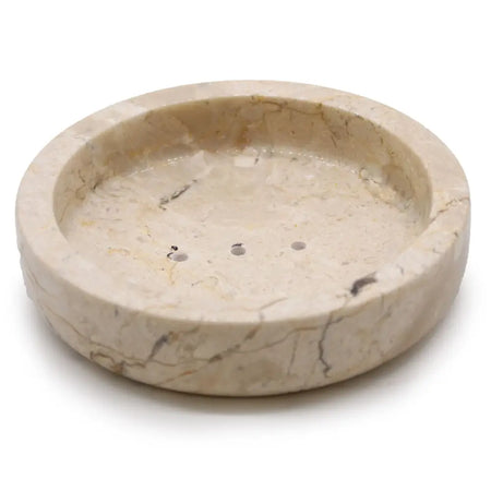 Round cream-colored honey marble soap dish with subtle veining and three drainage holes for bathroom use