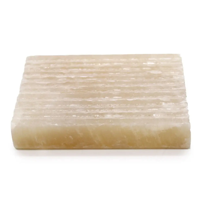 A rectangular translucent off-white honey onyx soap dish with a textured surface of parallel ridges