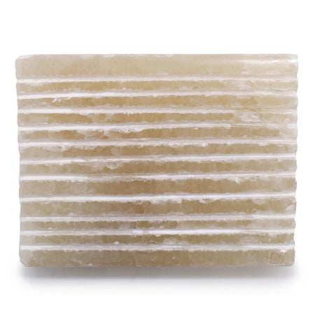 A rectangular translucent honey onyx soap dish with horizontal ridges and a natural rough stone texture