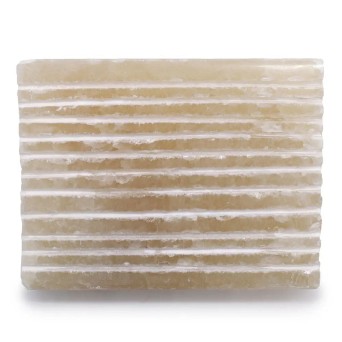 A rectangular translucent honey onyx soap dish with horizontal ridges and a natural rough stone texture