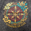 A charcoal stonewashed cotton t-shirt with a dark gray texture and a compass of life design in gold and teal accents