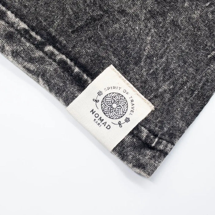 A charcoal stonewashed cotton t-shirt with black and white heathered fabric and a cream woven nomad sari label