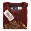 A folded maroon stonewashed cotton t-shirt with a gold geometric mandala and freedom text by nomad sari