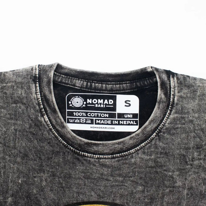 A faded charcoal stonewashed cotton t-shirt with a distressed texture and nomad sari label made in nepal in small size