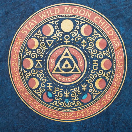 A stonewashed cotton t-shirt in blue with a wild moon child design and stay wild moon gold lettering on the front