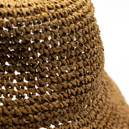 A woven straw sun hat in natural coffee tones with a textured interlaced pattern and natural brown material