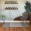 Gray eames style chair with wooden legs and black metal supports on a grey and white striped indian cotton rug